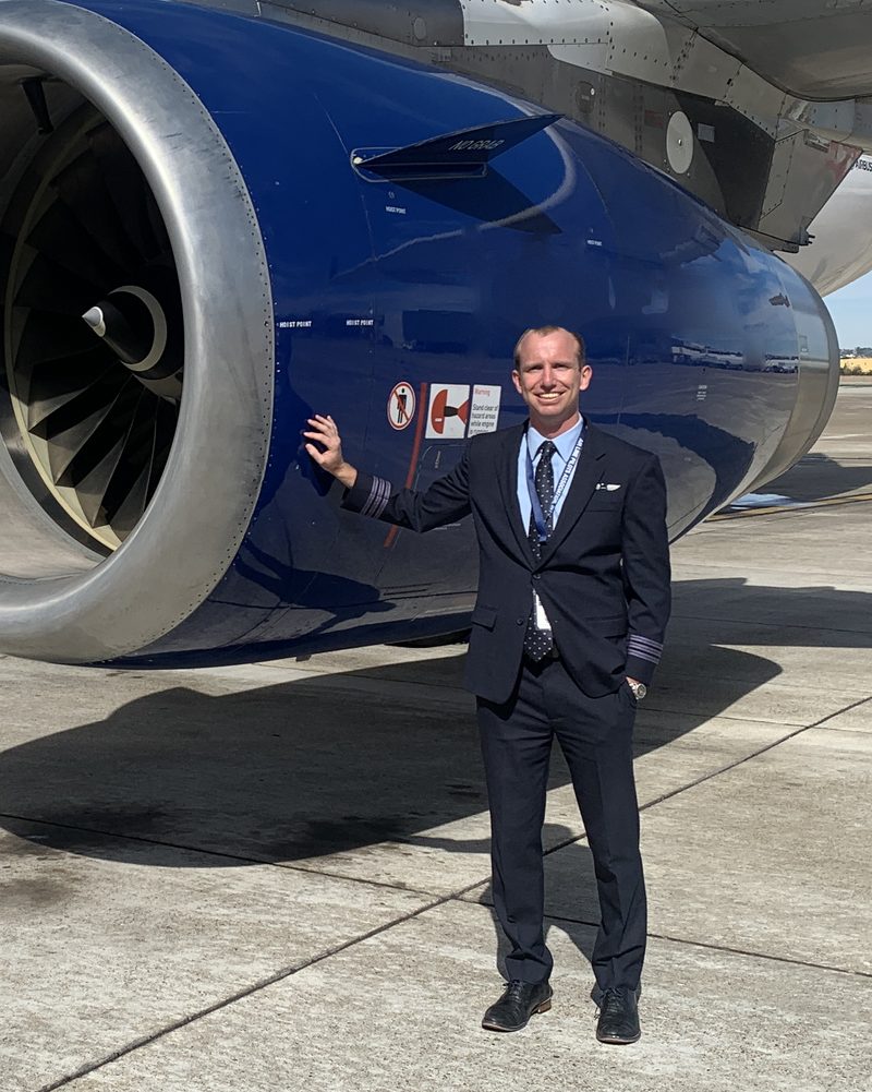 Alex Hedbany in airline uniform beside an Airbus A320 engine
